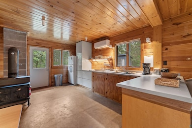 Kitchen with a wood stove, freestanding refrigerator, a wall mounted AC, plenty of natural light, and wood walls