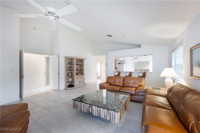 Tiled living room featuring ceiling fan and vaulte
