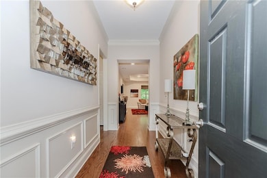 Entrance foyer featuring ornamental molding, wood finished floors, and wainscoting