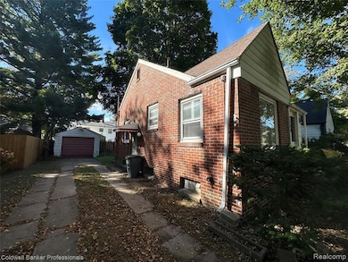 View of property exterior featuring brick siding, an outdoor structure, a garage, driveway, and a shingled roof