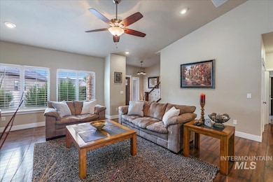 Living room featuring dark wood-style flooring, stairs, ceiling fan, vaulted ceiling, and recessed lighting