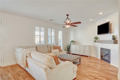 Living area with a ceiling fan, light wood-type fl