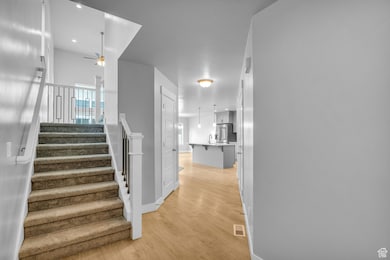 Stairs with wood finished floors and a ceiling fan