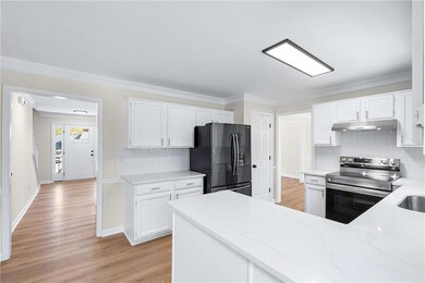 Kitchen featuring backsplash, stainless steel range with electric stovetop, white cabinets, ornamental molding, and freestanding refrigerator