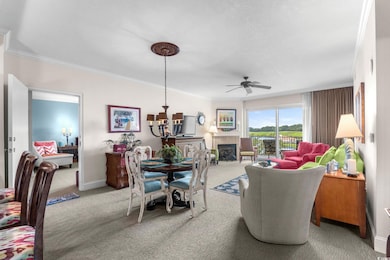 Living area with ornamental molding, carpet flooring, a fireplace with flush hearth, and ceiling fan