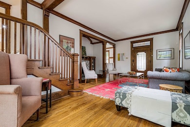 Living room featuring crown molding, light wood finished floors, and stairway