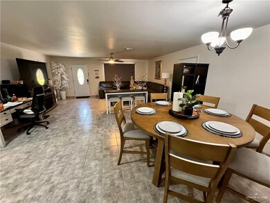 Dining space with light tile patterned flooring and ceiling fan with notable chandelier