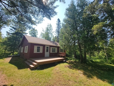 Rear view of property featuring a wooden deck, a yard, and a shingled roof