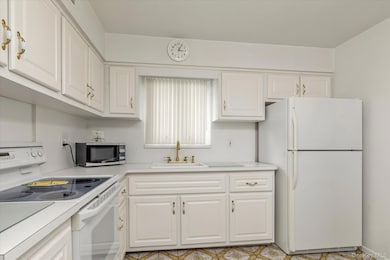Kitchen with white appliances, white cabinets, and light countertops