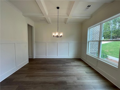 Unfurnished dining area with a decorative wall, coffered ceiling, plenty of natural light, a chandelier, and beamed ceiling