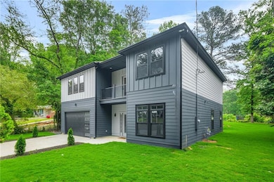 Rear view of house with a garage, a balcony, board