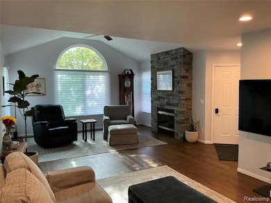 Engineered wood flooring, fireplace, Vaulted ceiling, recessed lighting, and a ceiling fan