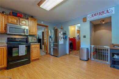 Kitchen with appliances with stainless steel finishes, light wood-style flooring, washer / dryer, and brown cabinets