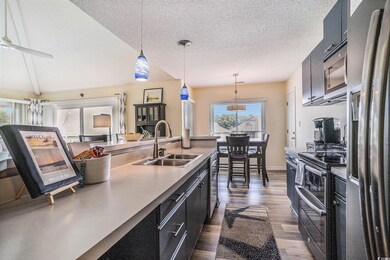 Kitchen featuring dark cabinets, decorative light fixtures, appliances with stainless steel finishes, dark wood-style floors, and a textured ceiling