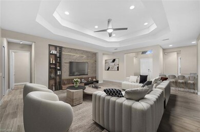 Living area with a tray ceiling, baseboards, recessed lighting, ceiling fan, and wood finished floors