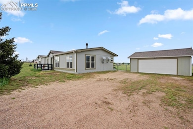 Rear view of property with driveway, a garage, and an outdoor structure
