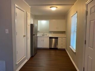 Kitchen with white cabinetry, stainless steel appliances, dark hardwood / wood-style floors, and crown molding