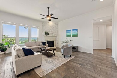 Living room featuring a ceiling fan, ornamental molding, a fireplace, baseboards, and wood finished floors