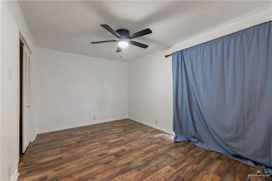 Unfurnished bedroom featuring dark wood-type flooring, ceiling fan, and a closet