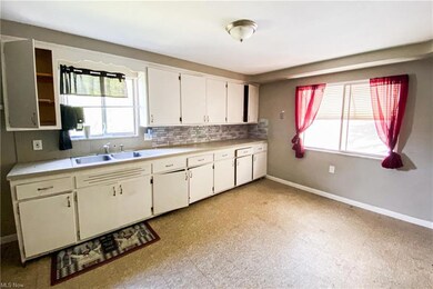 Kitchen with white cabinetry, backsplash, and ligh