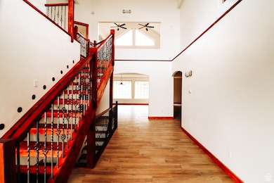 Stairway featuring a high ceiling, plenty of natural light, arched walkways, and wood finished floors