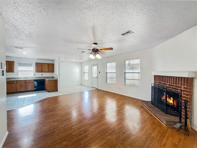 Unfurnished living room with light wood-style flooring, a fireplace, a textured ceiling, and a ceiling fan