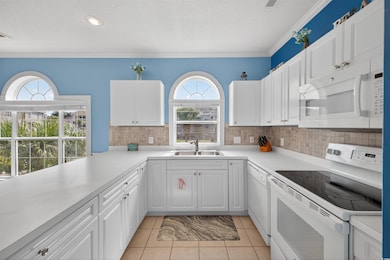 Kitchen featuring white appliances, crown molding, light countertops, a textured ceiling, and white cabinetry