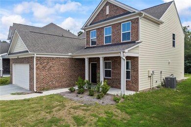 View of front of property with an attached garage, a front yard, a shingled roof, covered porch, and brick siding