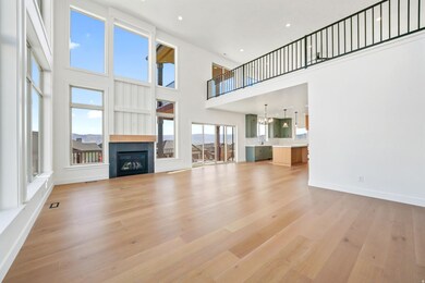 Unfurnished living room featuring a glass covered fireplace, a high ceiling, light wood-style floors, recessed lighting, and a chandelier
