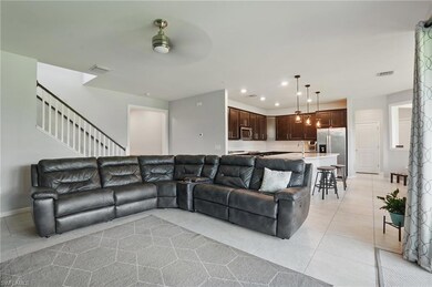 Living area featuring light tile patterned floors, ceiling fan, recessed lighting, stairway, and baseboards