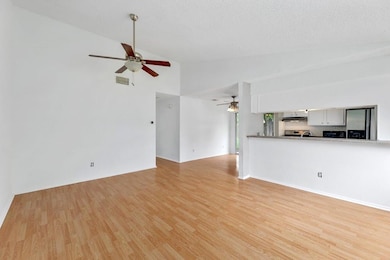 Unfurnished living room with light wood-type flooring, a ceiling fan, and high vaulted ceiling