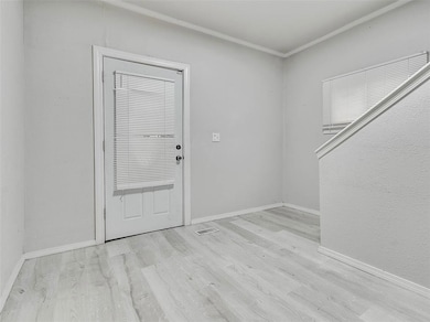Foyer entrance featuring light wood-style flooring and crown molding