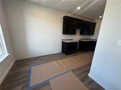 Kitchen with dark wood-type flooring, dark cabinets, recessed lighting, and light countertops