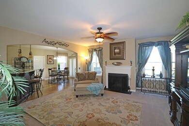 Spacious Greatroom with gas fireplace, decorative mantle, plush carpeting, two oversized single windows with faux wood blinds, arched opening into the Kitchen/Breakfast Area, and opens to the Foyer.  
