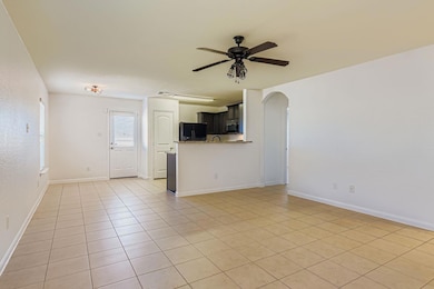 Unfurnished living room with arched walkways, light tile patterned floors, and a ceiling fan
