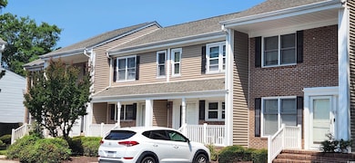View of front of property with a porch, brick siding, and roof with shingles