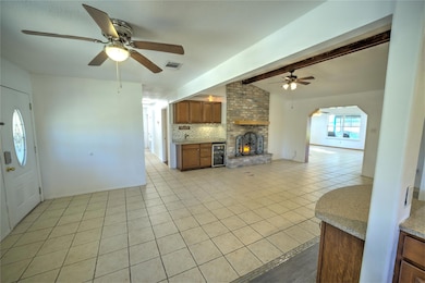 Unfurnished living room featuring light tile patterned floors, ceiling fan, wine cooler, arched walkways, and a fireplace
