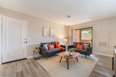 Living room with visible vents, light wood-style f