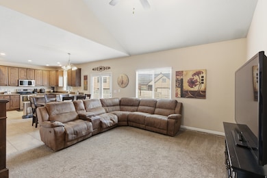 Living room featuring light colored carpet, a chandelier, vaulted ceiling, recessed lighting, and ceiling fan