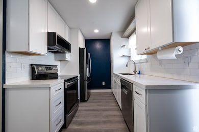 Kitchen with decorative backsplash, appliances with stainless steel finishes, light stone counters, and recessed lighting