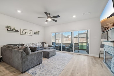 Living area featuring light wood-type flooring, a stone fireplace, recessed lighting, and a ceiling fan
