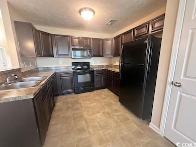 Kitchen with black appliances, a textured ceiling, and dark brown cabinetry