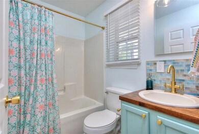 Bathroom featuring decorative backsplash, toilet, vanity, and shower / bathtub combination with curtain