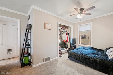 Bedroom with crown molding, wood walls, carpet, a closet, and a ceiling fan