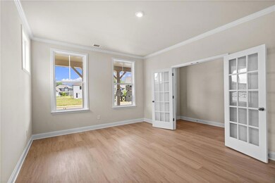 Empty room with french doors, crown molding, light wood-type flooring, and baseboards