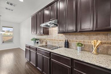 Kitchen featuring under cabinet range hood, baseb