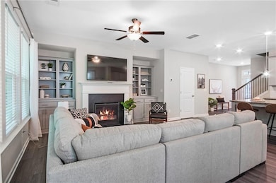 Living room featuring built in shelves, dark hardw