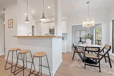 Kitchen featuring a breakfast bar area, white cabinetry, light wood-type flooring, hanging light fixtures, and a chandelier