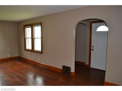 Foyer has arched doorways and leads to large living area with hardwood floors