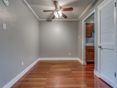Spare room with hardwood / wood-style flooring, crown molding, a ceiling fan, and a textured wall
